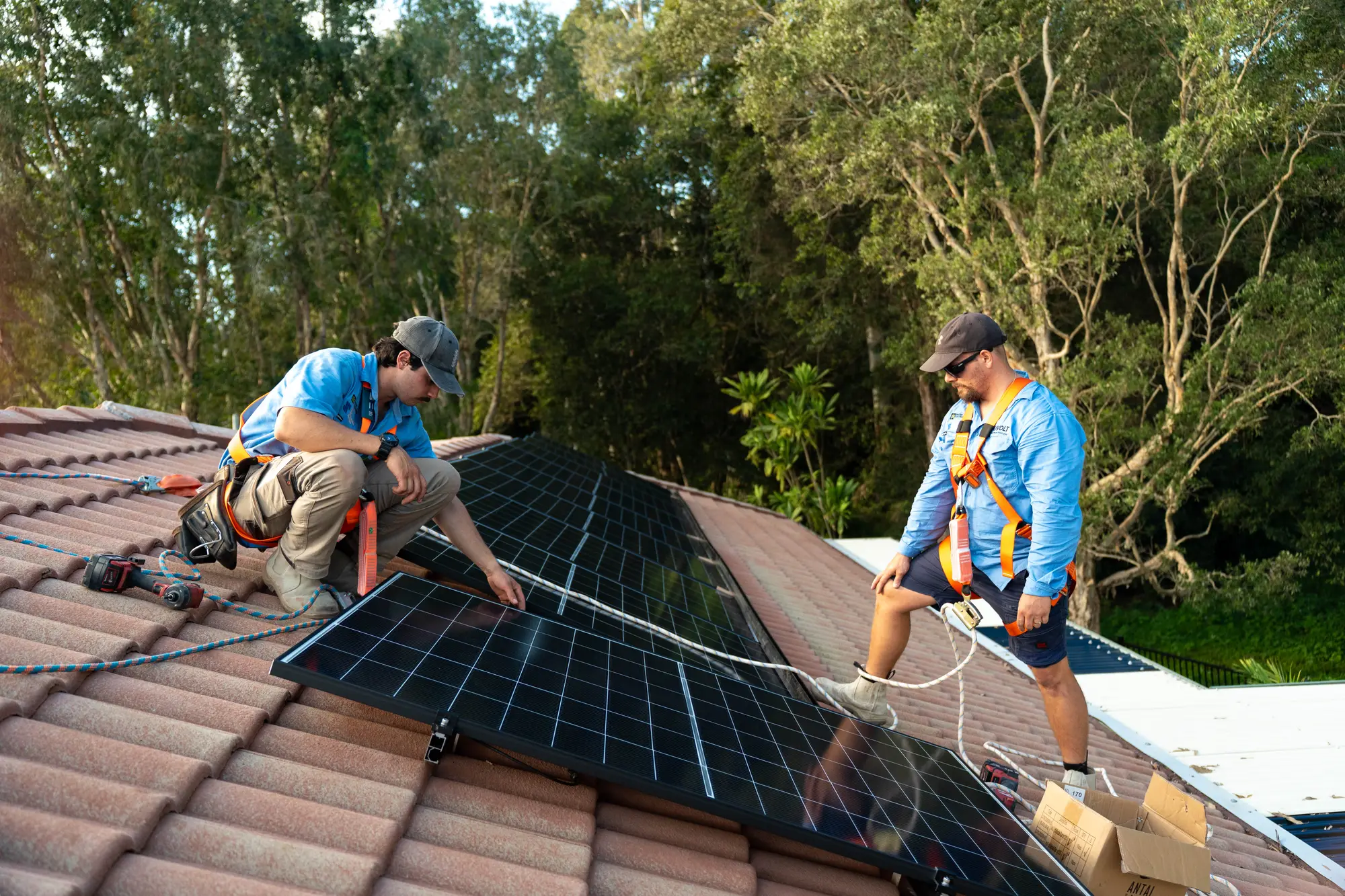 Dan and a Nuvolt team member in safety harnesses laying solar panels on a tiled roof